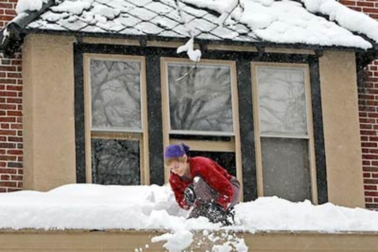 In Phoenixville, Laura Wildman clears heavy snow off her roof on Wednesday, Feb. 10, 2010. But there is a bright side to all the white stuff. (Steven M. Falk / Staff Photographer)
