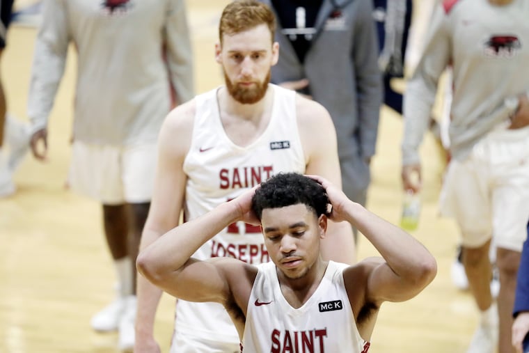 Jared Bynum (foreground) and Anthonty Longpre walk off the court after George Washington beat St. Joe's on Sunday.