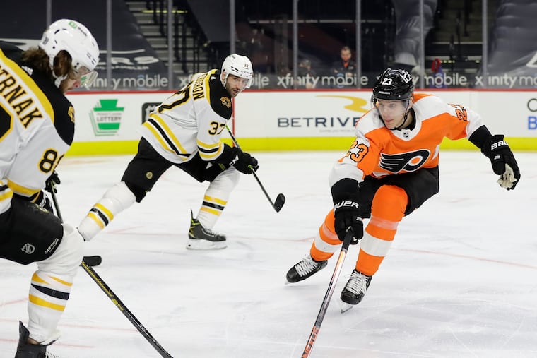 Flyers left winger Oskar Lindblom (right) goes after the puck against Boston right winger David Pastrnak (left) as Patrice Bergeron (37) heads up ice in the Bruins' 2-1 victory Friday.