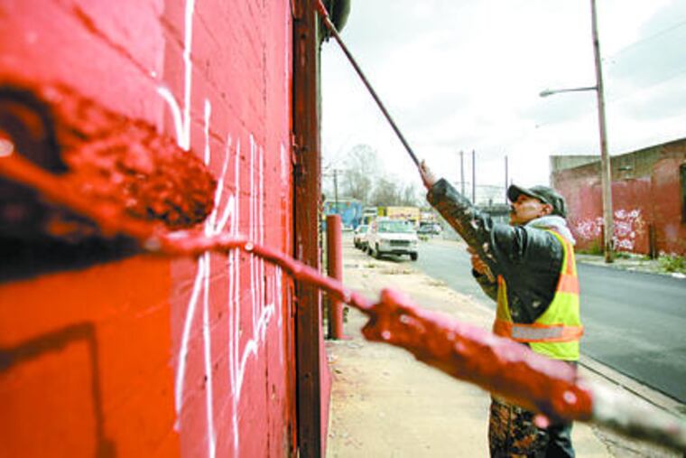 Edguardo Diaz, working on Westmoreland Street, is on one of Philadelphia's dozen crews that wipe out graffiti.