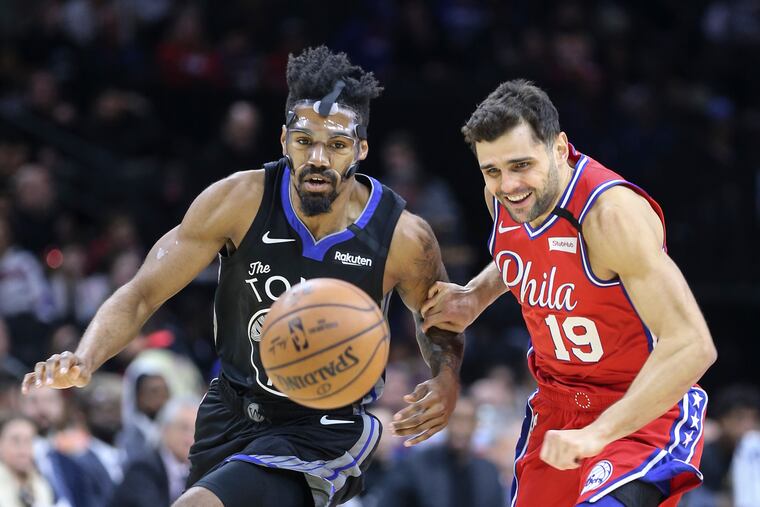 The Sixers' Raul Neto goes for a loose ball with the Warriors' Jacob Evans during the first quarter.