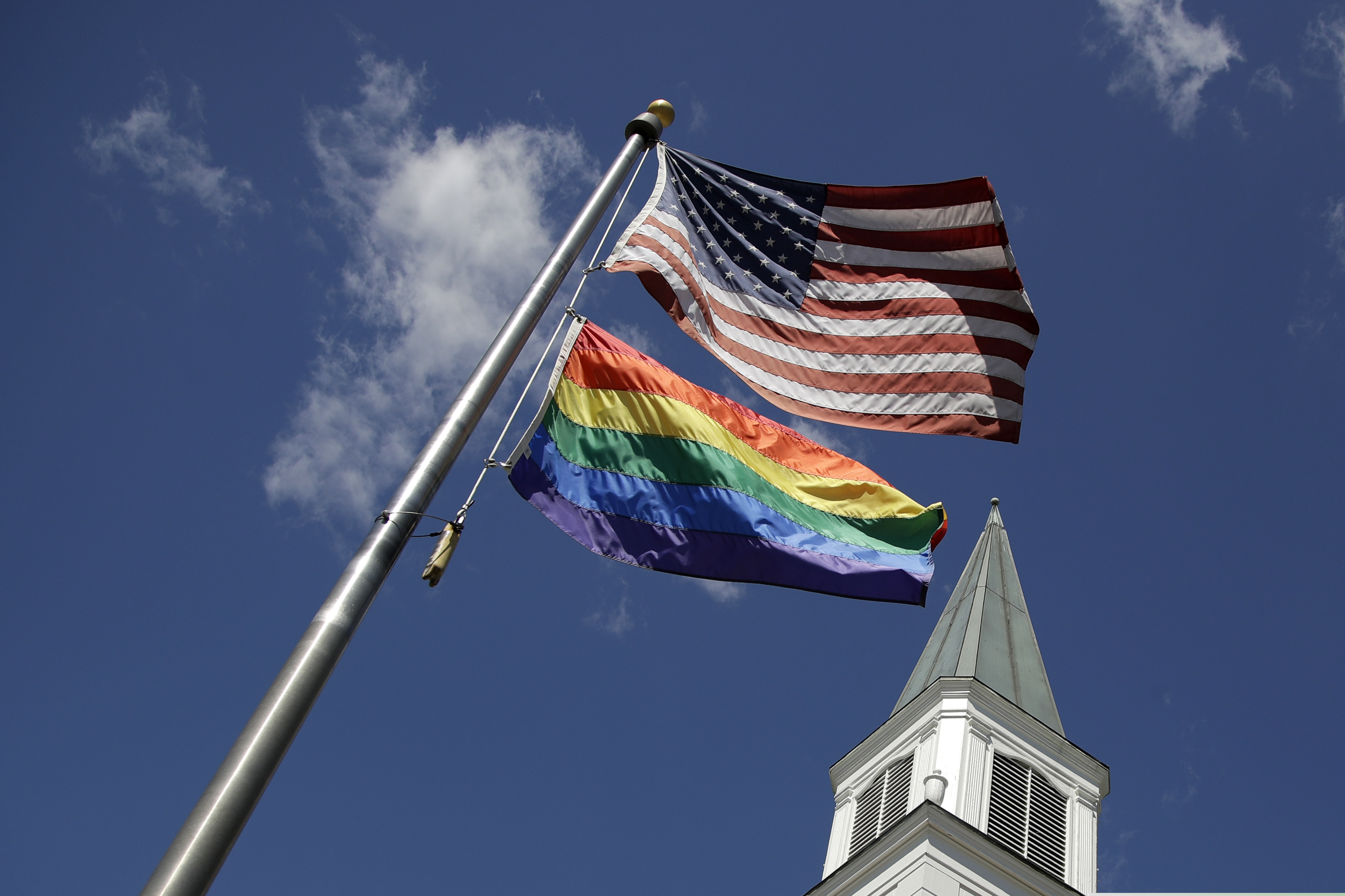 A gay pride rainbow flag flies along with the U.S. flag in front of the Asbury United Methodist Church in Prairie Village, Kan., on Friday, April 19, 2019. (AP Photo/Charlie Riedel)
