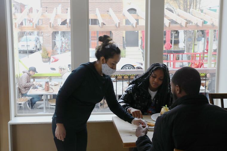 Server Jeni Cero (left) brings food to Siani Davis (center) and her boyfriend, Troy Richardson, during lunchtime at Green Eggs Cafe on Dickinson Street in South Philadelphia last month.