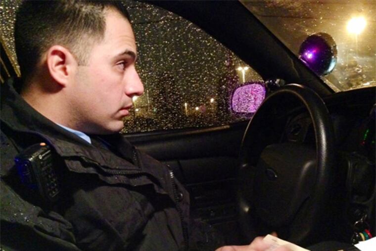 Officer Michael Levin keeps an eye out during a car stop as he writes a ticket for a man who made a brazen illegal U-turn on Wissahickon Avenue Tuesday night. (Morgan Zalot / Daily News Staff)