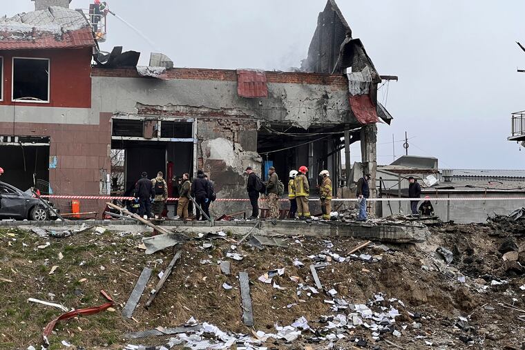 Emergency workers clear up debris after an airstrike hit a tire shop in the western city of Lviv, Ukraine, on Monday.