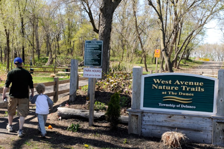 Joe Kilcoyne, of Middletown, Md., walks with his son Edward, 5, in the Delaware River area of Delanco known as the "Dunes," April 24, 2014. He grew up in town and was visiting his parents. A judge recently decided the area belongs to NJ, not Delanco, and can be cleared of its woods and hiking trails so that a dumping ground for dredge spoils can be created. (TOM GRALISH/Staff Photographer)