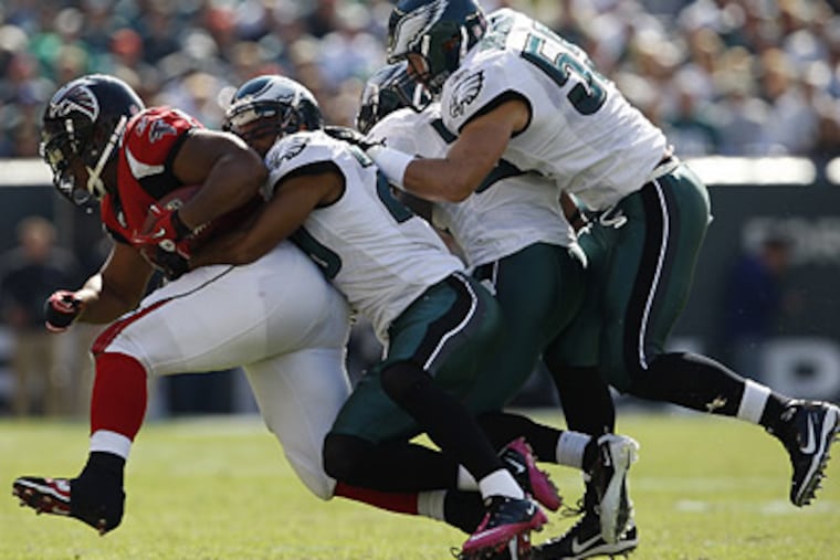 Nate Allen, Quintin Mikell and Stewart Bradley tackle the Falcons' Michael Turner during today's game. (David Maialetti / Staff Photographer)