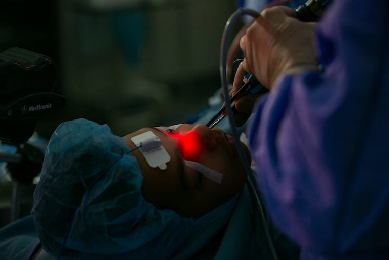 James Palmer, director of rhinology at Penn Medicine, works to improve sinus drainage for Dawit Debebe, 14, who had a severe reaction to fungus in his nose.