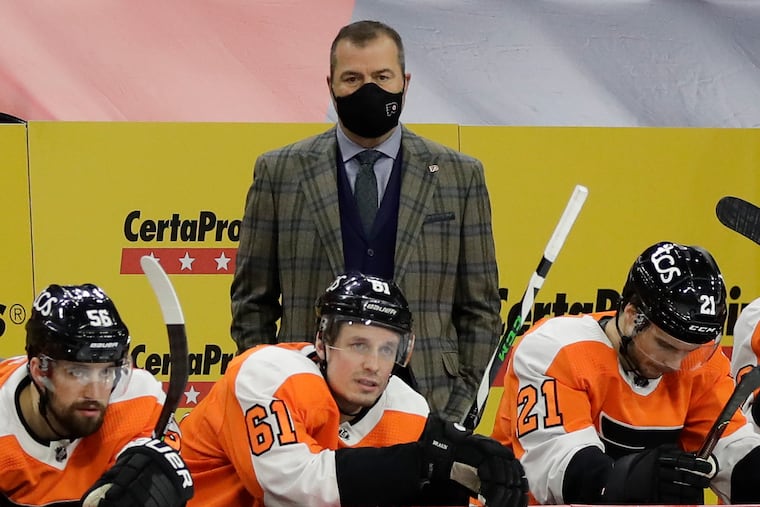 Flyers coach Alain Vigneault watches his team play the Boston Bruins with Flyers defensemen Erik Gustafsson, Justin Braun and center Scott Laughton on the bench on Feb. 5.