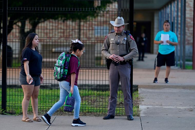 Students arrive at Uvalde Elementary, now protected by a fence and Texas State Troopers, for the first day of school on Tuesday.