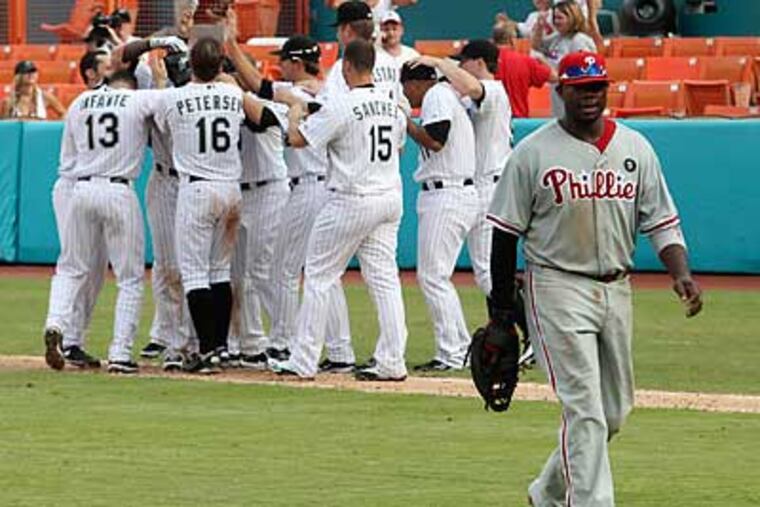 Ryan Howard walks off the field as the Marlins celebrate after winning in the 14th inning. (Hector Gabino/AP)