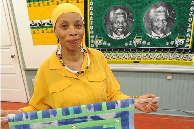 Betty Leacraft holds a quilt she made titled "Talking Mask with Cowrie Shells." ( CLEM MURRAY / Staff Photographer )