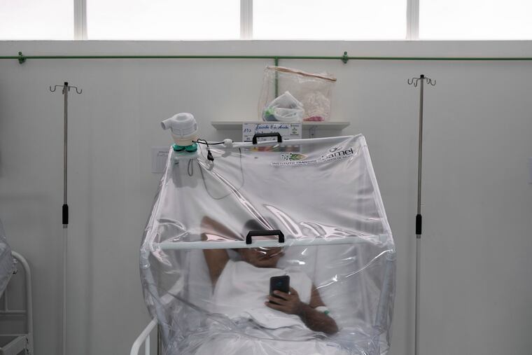 A COVID-19 patient uses his phone as he is treated inside a non-invasive ventilation system named the "Vanessa Capsule" at the municipal field hospital Gilberto Novaes in Manaus, Brazil on Monday.