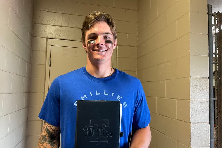 Phillies center fielder Mickey Moniak poses with the black journal he's used this offseason and spring training