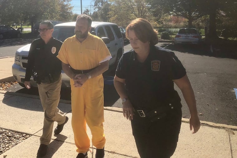 David Allen Hamilton Jr. is escorted into district court in Doylestown on Tuesday. Hamilton is accused of assaulting a police officer and stealing a car during a week-long manhunt for him in Bucks County.