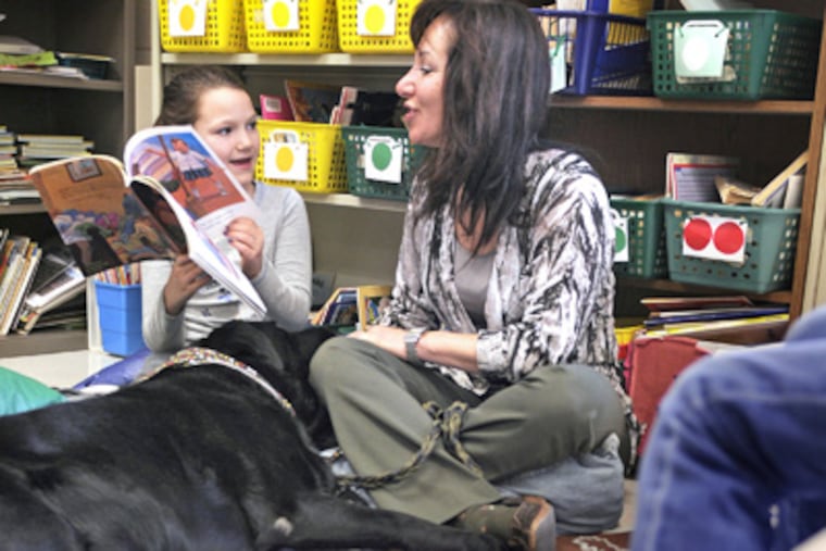 Maggie Burke, 8, reads to Wendi Huttner and a Lab named Wes in Richboro. Huttner's program helps youngsters overcome anxiety by reading to dogs. (Tom Gralish / Staff Photographer)