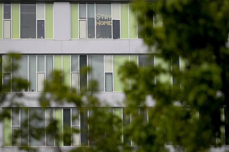 A sign in a window of the Goldtex apartment building on North 12th Street in Philadelphia encourages people to “stay home” during the coronavirus outbreak. The city's Eviction Diversion Program aims to prevent lockouts and keep tenants in their homes.