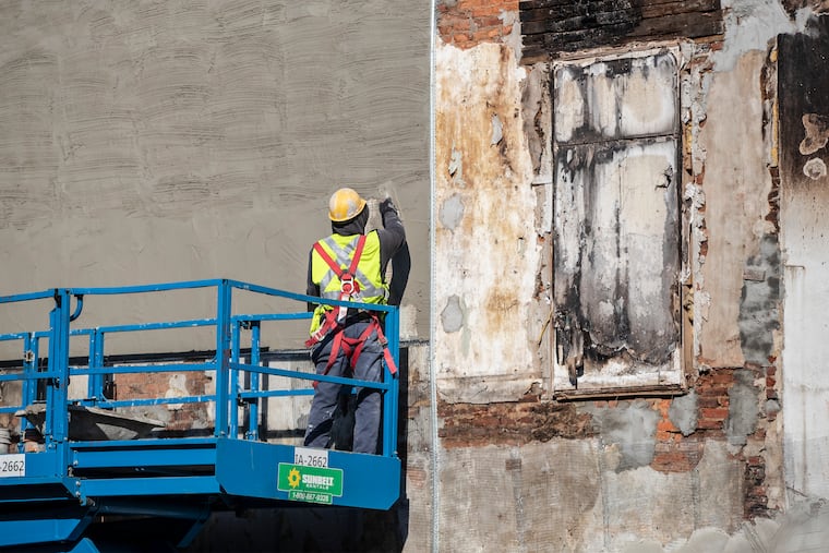 In January 2020, a construction worker for Verdi Construction applies a stucco coating to the exposed side of a house that had bordered five homes demolished in the aftermath of an explosion on Eighth Street.