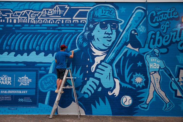 Paul Carpenter works on his mural at 20th Street and Oregon Avenue on Thursday. Carpenter created the artwork for Deer Park's limited-edition water bottles and is scaling it for a South Philly wall.