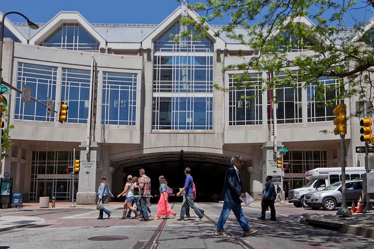 Pedestrian walking on Arch and 12th streets with the Pennsylvania Convention Center in the background, May 6, 2014. ( DAVID M WARREN / Staff Photographer )
