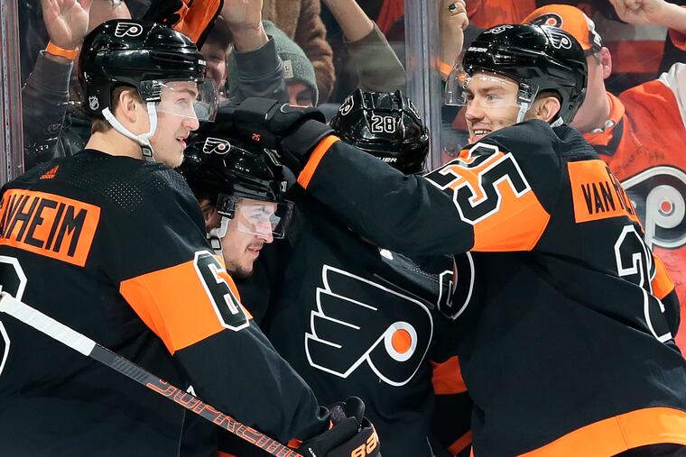 Hugs all around: Defenseman Travis Sanheim embraces forwards (from left) Travis Konecy, Claude Giroux and James van Riesdyk during Saturday's win over Los Angeles.