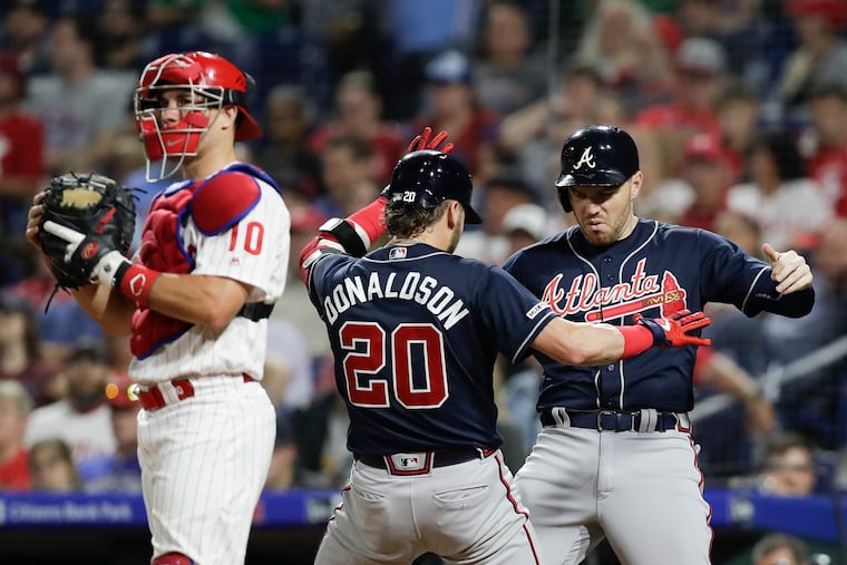Atlanta's Josh Donaldson celebrates his three-run, seventh-inning home run with teammate Freddie Freeman while Phillies catcher J.T. Realmuto waits for the next at bat Monday night.