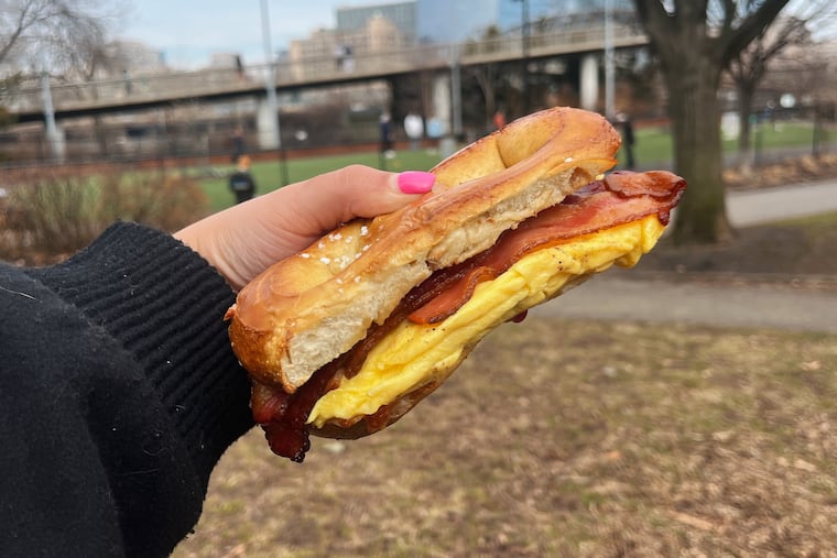 A bacon, egg, and cheese breakfast sandwich on a salted pretzel from Rowhome Coffee.