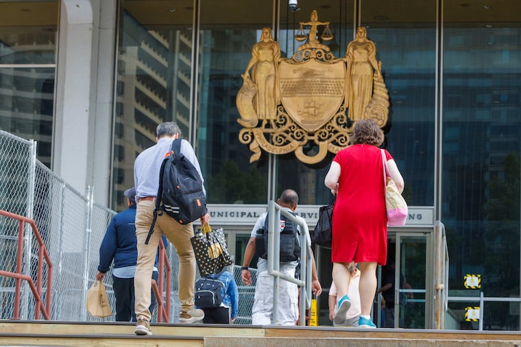 Workers walking into Municipal Services Building at 15th and JFK Blvd on Monday morning. The mayor has asked that city workers return to offices today.