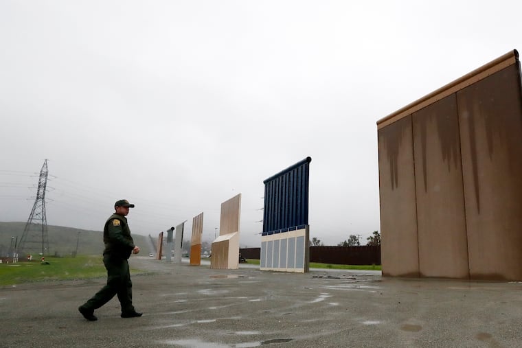 FILE - In this Feb. 5, 2019 file photo a Border Patrol agent walks towards prototypes for a border wall in San Diego. The Trump administration on Wednesday, Feb. 27 plans to demolish eight prototypes of the president's prized border wall that the government built near San Diego one year ago.