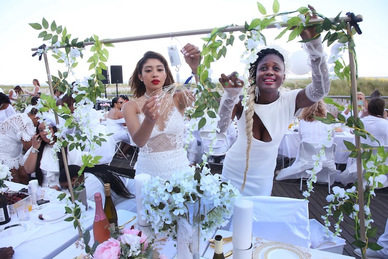 Sasha Couillard, left, and Akeesha Washington, both f Phila., decorate their table at the Diner En Blanc, in Atlantic City, Saturday, June 25, 2022.