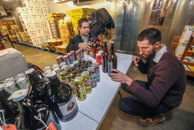 Working in the basement freezer of Iovine’s Produce, under the Reading Terminal Market, Evan Dellaera (right) and Bill Buckman tape the corresponding numbers to the corresponding beer entries from local breweries in preparation for the judging in this year’s ninth annual Brewvitational competition.