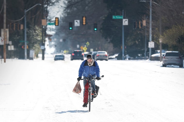 Jean Christophe rides his bike home from Kroger on snow and ice in Memphis on Wednesday.