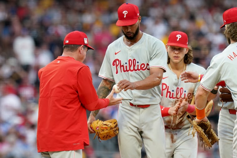 Cristopher Sánchez, center, hands the ball to manager Rob Thomson, left, as he exits the game during the sixth inning.