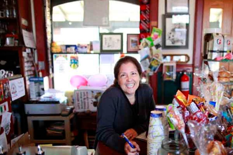 Owner Jovanna Acchione smiles behind the counter. For decades the Wayne train station was a dead space wrapped around a ticket window. Now it is the venue for a hotspot cafe during the morning and a weekend night spot. The owners, along with other businesses along the old Main Line train run, are reaping a harvest from the transit oriented development phenomenon, April 26, 2013. ( DAVID SWANSON / Staff Photographer )