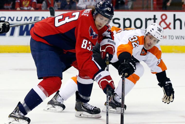 Capitals center Jay Beagle (83) works the puck as he is defended by Philadelphia Flyers defenseman Mark Streit (32), from Switzerland, in the first period of an NHL hockey game, Sunday, Dec. 15, 2013, in Washington. (Alex Brandon/AP)