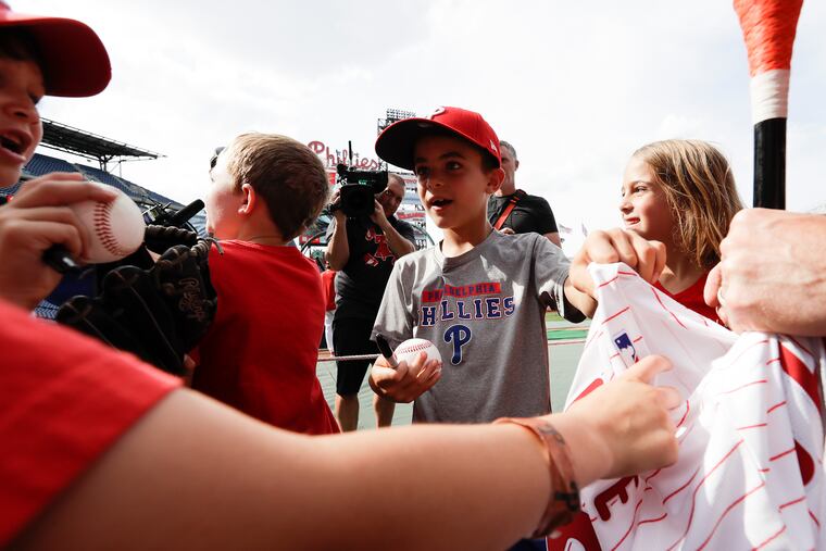 Caden Marge (center) touches an autographed jersey from Bryson Stott before the Phillies played the Diamondbacks on Friday.