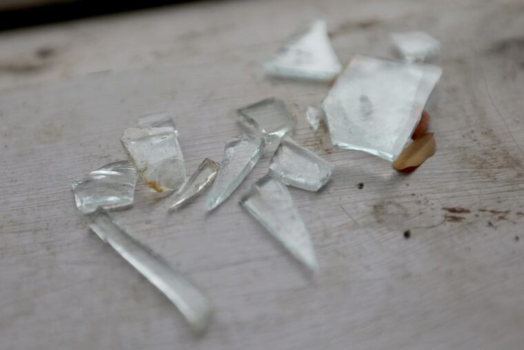 Pieces of glass rest on the windowsill of a home. The owner alleges drug dealers threw a Molotov cocktail through the window.