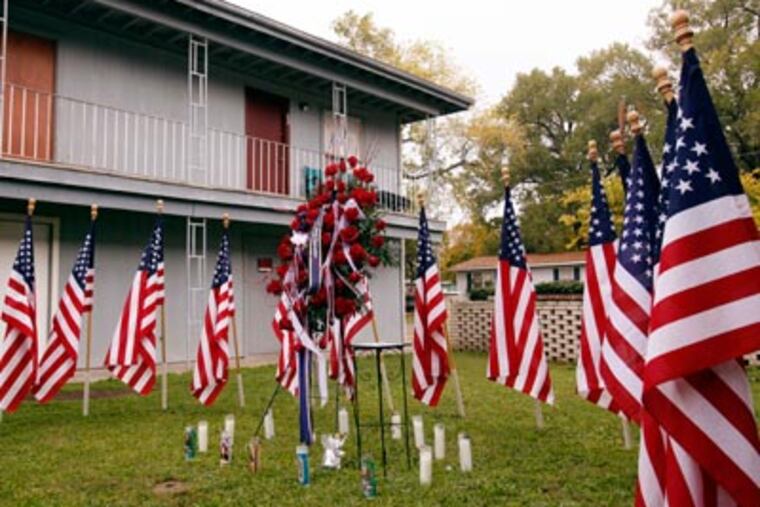 Thirteen flags and flowers are shown at the apartment complex where Army psychiatrist Maj. Nidal Malik Hasan lived outside of Fort Hood. (AP Photo/Paul Sakuma)