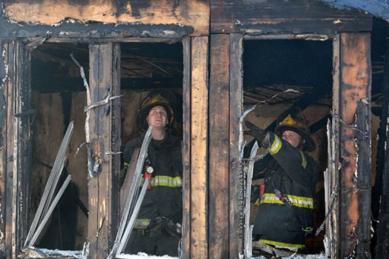 Firefighters work at the scene of fire that ripped through eight rowhomes in Southwest Philadelphia killing four children July 5, 2014. ( TOM GRALISH / Staff Photographer )