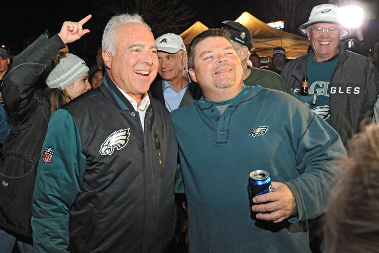 Eagles owner Jeffrey Lurie (left), with fan Tom Baynes, has reason to smile. The team's value is up 900 percent since he bought it in 1994. NFL players' salaries have not risen at the same rate.