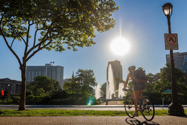 A cyclist crosses Logan Square toward Swann Memorial Fountain as the sun rises on May 4.