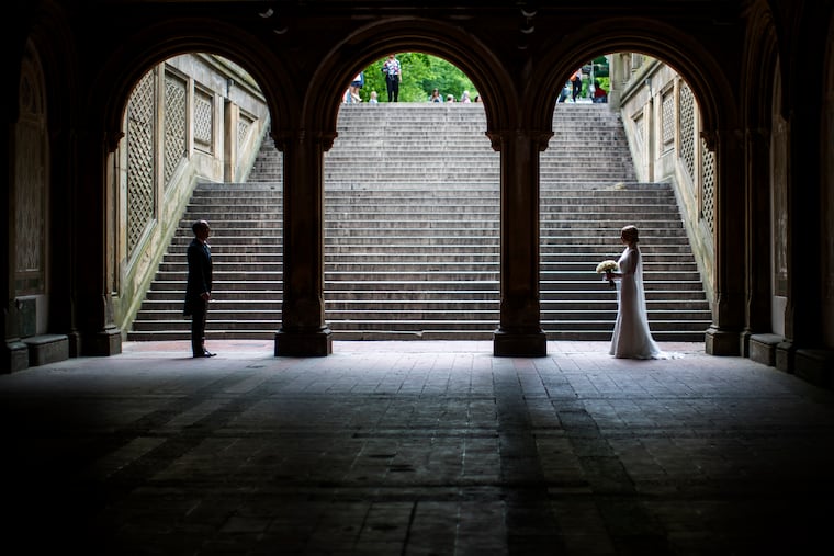 FILE - In this Tuesday, May 23, 2017 file photo, a bride and groom pose for wedding pictures at the Bethesda Terrace in New York's Central Park. Now that most Americans have been ordered to stay at home and avoid nonessential travel to slow the spread of the COVID-19 coronavirus in 2020, many couples — including those who were only days or weeks away from getting married — have had to abruptly postpone their special day, while many others are in limbo, unsure of how to proceed. (AP Photo/Mary Altaffer)