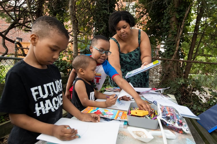 Philadelphia schools, like many in the region and across the nation, have seen a significant drop this year in kindergarteners. Domonique Goines' son Leonard Thomas-Bright, 6 (at left) would be attending kindergarten in the Philadelphia School District this year if not for the pandemic. Instead, his mother, at right, is homeschooling him and his brothers Isaac, 4, and Eli, 8.