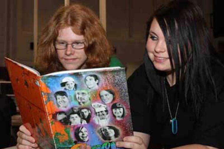 Joey Hudson , who worked on the yearbook before graduating, and Heather Knapp, a section editor, look over the production.