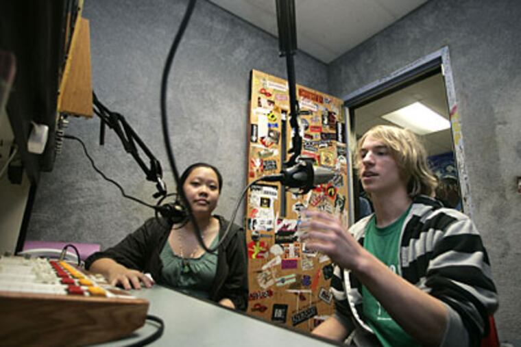 Haverford High School's Carol Ly and Zach Kuntz, both 17, in the WHHS booth. Ly is a promotions director. Kuntz has a sports and news show on the station, which is marking its 60th anniversary. (DAVID SWANSON / Staff Photographer)