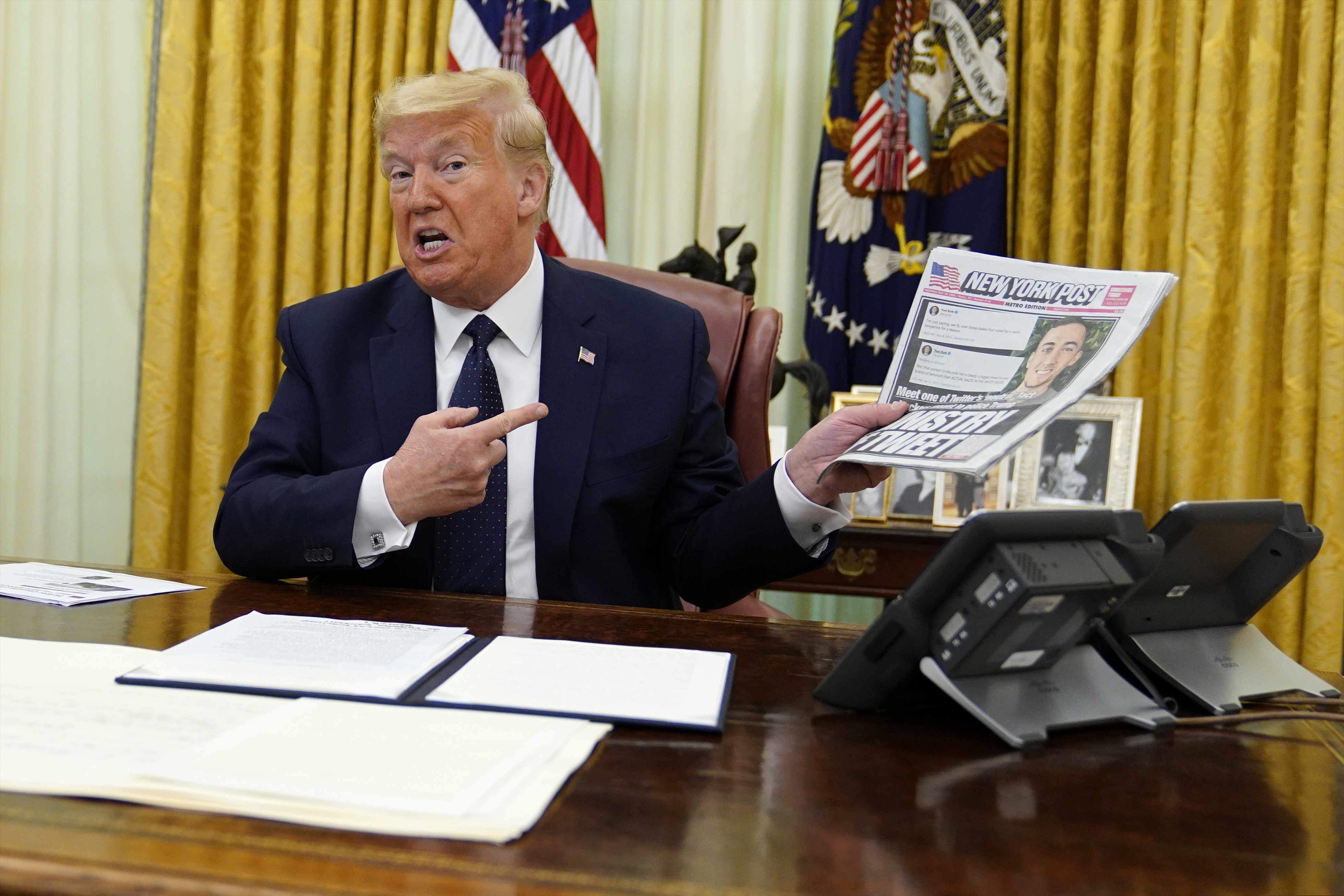 President Donald Trump holds up a copy of the New York Post as speaks before signing an executive order aimed at curbing protections for social media giants.