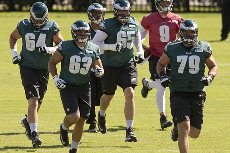 Eagles offensive tackle Lane Johnson (65) along with tackle Matt Tobin (64), center David Molk (63), wide receiver Jordan Matthews (center back), quarterback Nick Foles (9), and guard Todd Herremans (79) run to their next drill during practice. (Matt Rourke/AP)