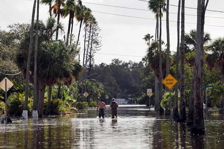 Men walk down a street flooded by Hurricane Helene in the Shore Acres neighborhood of St. Petersburg, Fla., on Sept. 27, 2024.