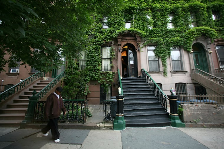 FILE - In this June 13, 2007, file photo, a youth walks by the Langston Hughes House, center, covered in ivy, in New York's Harlem section. More than $1.6 million in grants are going to 22 sites and organizations to help preserve black history. The National Trust for Historic Preservation announced the grants Friday, July 5, 2019, during the 25th annual Essence Festival in New Orleans.