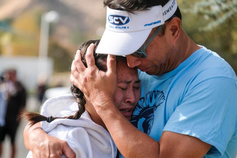 Ella Cabigting is embraced by her father Emerson as they reunite following a shooting at Saugus High School that injured several people, Thursday, Nov. 14, 2019, in Santa Clarita, Calif. (AP Photo/Ringo H.W. Chiu)